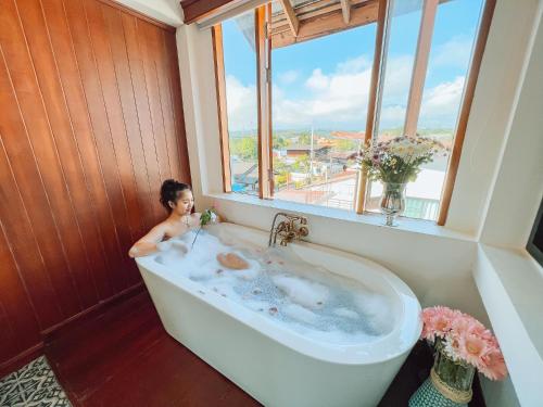 a woman in a bath tub in a room with a window at Pai Cherkaew Boutique House in Pai