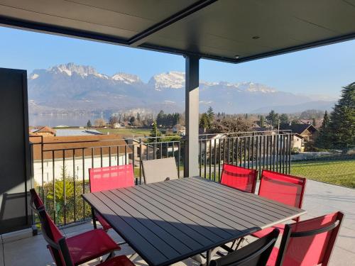 uma mesa e cadeiras num alpendre com vista para as montanhas em Appartement Thiou em Sévrier