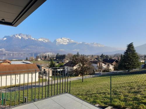 uma vista para as montanhas a partir de uma casa com uma cerca em Appartement Thiou em Sévrier