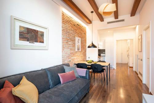 a living room with a blue couch and a brick wall at Aspasios Market Balconies Apartments in Barcelona