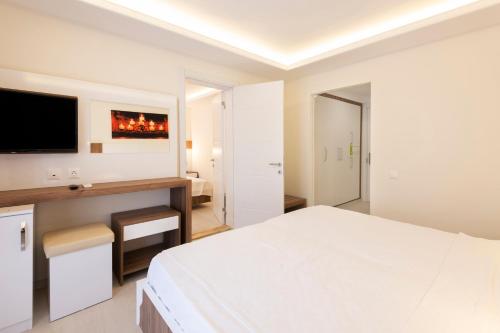 a white bedroom with a large bed and a desk at Soothe Hotel in Kalkan