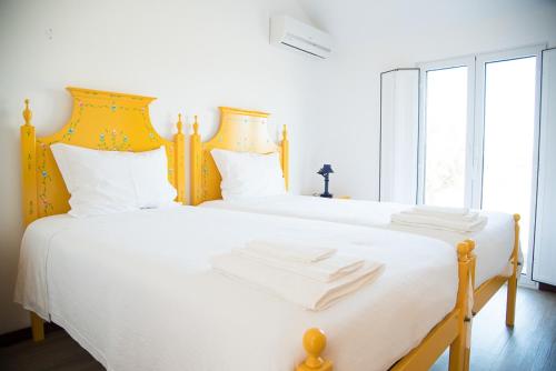 a bedroom with two beds with white sheets and a yellow headboard at Agro-Turismo Herdade do Carneiro in Escoural