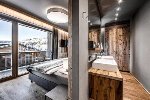 łazienka z łóżkiem, umywalką i oknem w obiekcie ALMMONTE SENSUM SUITES Boutique Hotel w mieście Wagrain