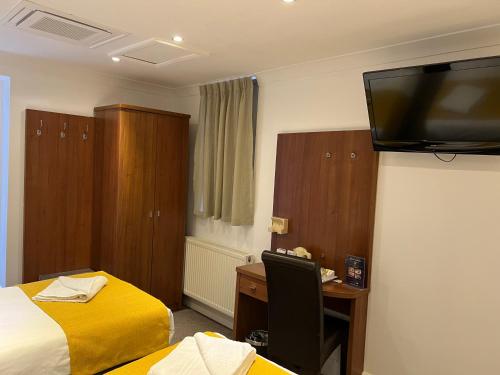 a hotel room with two beds and a desk and a television at Park Avenue Bayswater Inn Hyde Park in London