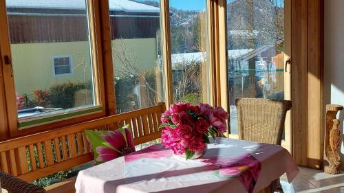 uma mesa com um vaso de flores num alpendre em Ferienwohnung Seeberg mit Almfeeling em Faistenau
