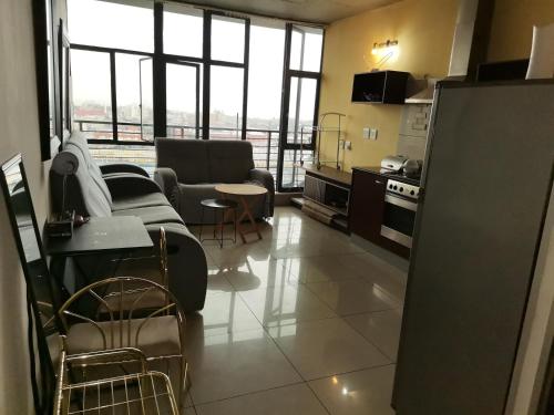 sala de estar con sofá y sillas y cocina en Broadway flats Braamfontain, en Johannesburgo