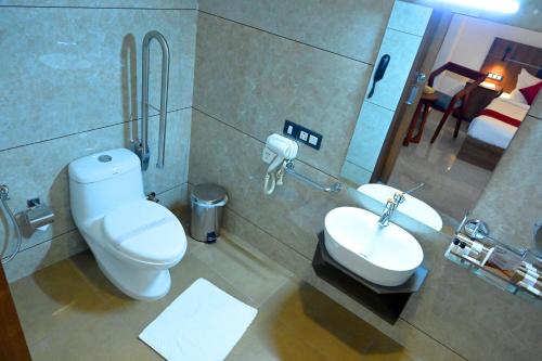 a bathroom with a toilet and a sink at Hotel Thamburu International in Trivandrum