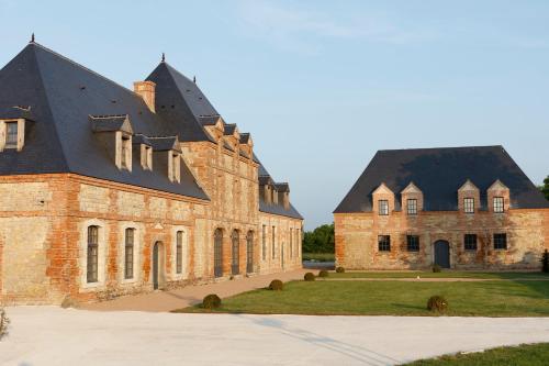 a large brick building with a black roof at Le Domaine de Ravenoville - Pierres d'Histoire in Ravenoville