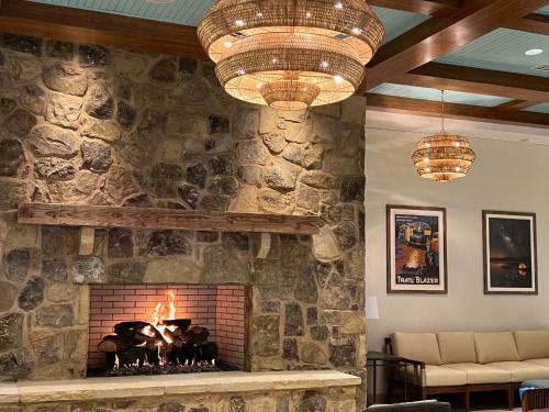 a stone fireplace in a living room with two chandeliers at The Lodge at Camp Margaritaville in Pigeon Forge