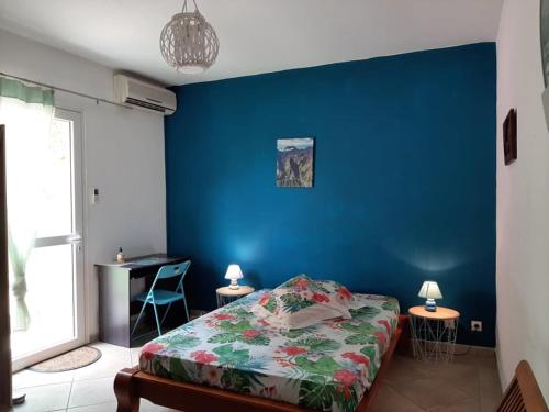 um quarto com uma parede azul, uma cama e uma secretária em lakazadom974 em Saint-Gilles-les Hauts
