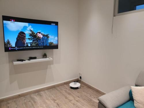 un salon avec une télévision à écran plat sur un mur blanc dans l'établissement Appartement COSY et chaleureux, à Lons-le-Saunier