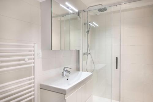 une salle de bain blanche avec un lavabo et une douche dans l'établissement Belle maison à 450m de la plage de la Baule, à La Baule