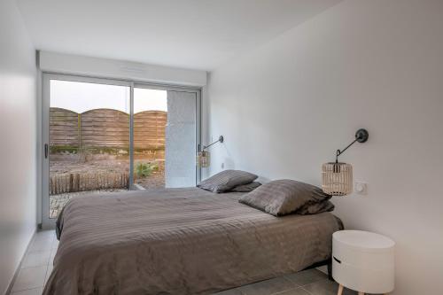 une chambre avec un grand lit et une grande fenêtre dans l'établissement Belle maison à 450m de la plage de la Baule, à La Baule