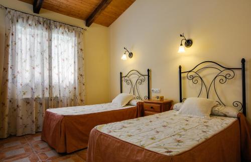 1 dormitorio con 2 camas y ventana en Casas Rurales Carroyosa del Jerte, en Navaconcejo