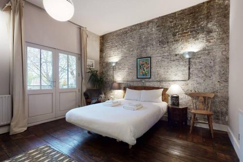 a bedroom with a white bed and a brick wall at Stylish 2 bedroom 2 bathroom flat in Islington in London