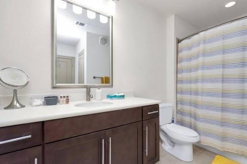 a bathroom with a sink and a toilet and a mirror at Stylish Open Concept Apt with King Bed, walking distance from NRG Texans Stadium, 1 mile to Med Center, Free Parking in Houston