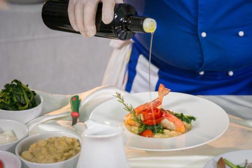 a person is pouring wine into a plate of food at Pizzomunno Vieste Palace Hotel in Vieste