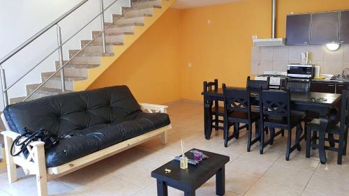 ein Wohnzimmer mit einem schwarzen Sofa und einem Tisch in der Unterkunft Maipu Alquiler Por Dia in Río Gallegos