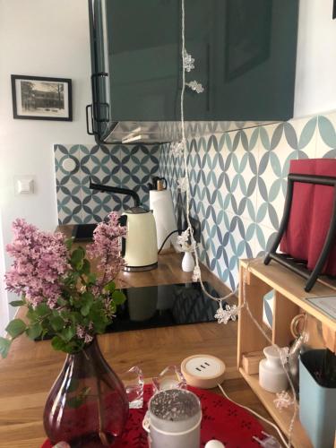 uma mesa com um vaso com flores roxas em Atelier Foto Lipowa - Apartamenty em Nałęczów