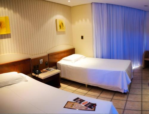 a hotel room with two beds and blue curtains at Pousada dos Girassóis in Palmas