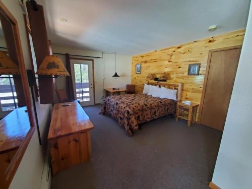 a bedroom with a bed and a wooden wall at Swiftcurrent Lodge in Estes Park