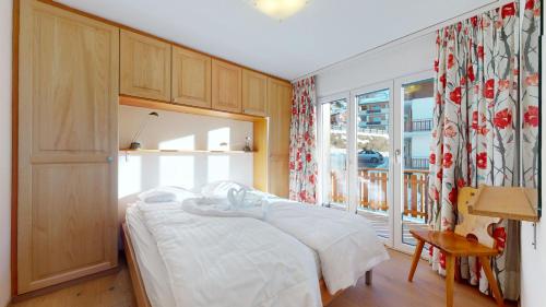a bedroom with a white bed and a window at Hortensia MOUNTAIN & CENTER apartments in Veysonnaz