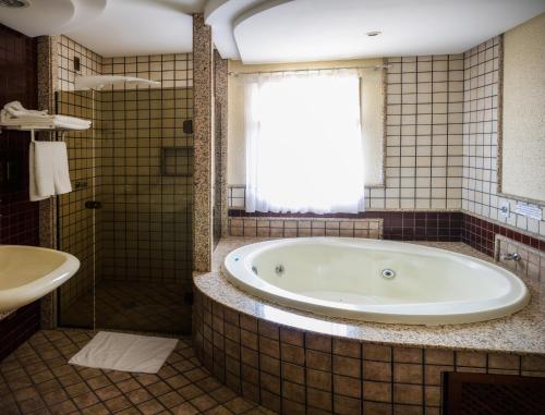 uma casa de banho com uma banheira, um chuveiro e um lavatório. em Pousada dos Girassóis em Palmas