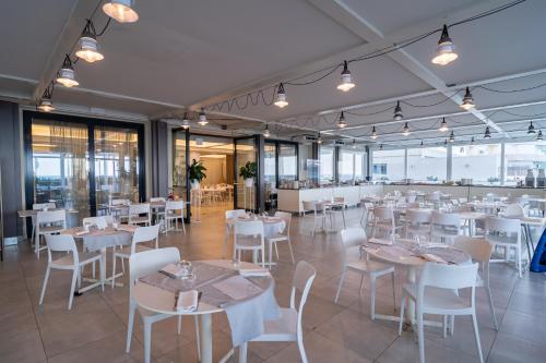 a restaurant with white tables and chairs and windows at Nautilus Family Hotel in Pesaro