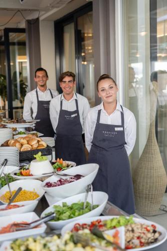 three men in aprons standing in front of a buffet of food at Nautilus Family Hotel in Pesaro