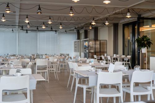 a dining room with white tables and white chairs at Nautilus Family Hotel in Pesaro