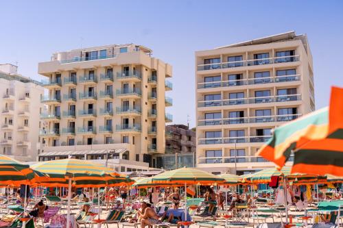 a beach with many chairs and umbrellas and buildings at Nautilus Family Hotel in Pesaro