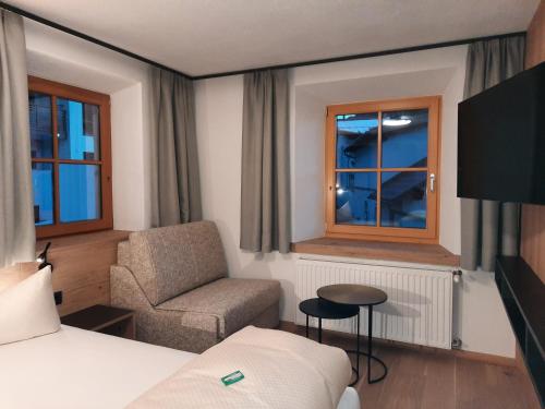 a hotel room with a bed and a chair and window at ROSENHOF- Premium & Landhaus Apartments & Wellness & Erlebnisbauernhof in Nauders