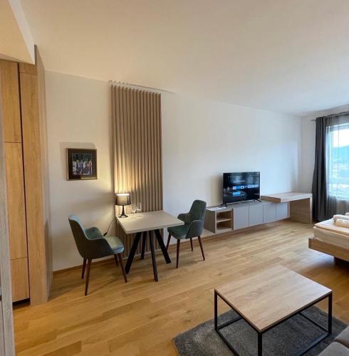 a living room with a table and chairs and a tv at Apartmani G8 in Pale
