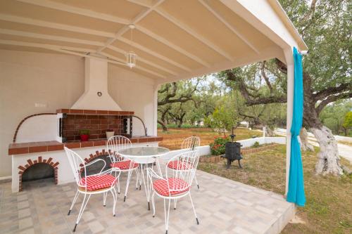 a patio with a table and chairs and a fireplace at Soso's Sea View Apartment in Plános
