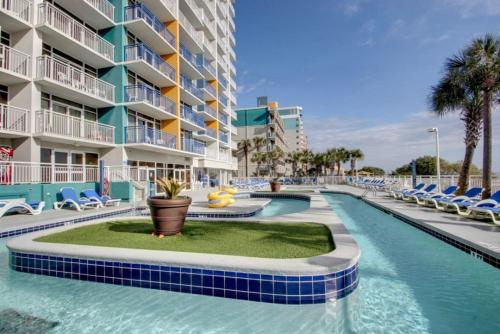 a swimming pool at a resort with chairs and a building at Hosteeva 1BR Oceanfront Condo in Atlantica Resort near Boardwalk in Myrtle Beach