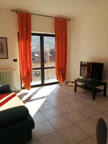 un soggiorno con una grande finestra con tende rosse di appartamento due - CIR 0007 ad Aosta