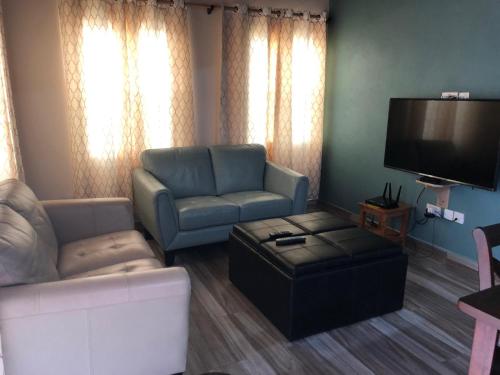 a living room with a couch and a tv at Cool Running Apartments in Saint Georgeʼs