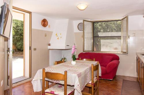 un soggiorno con tavolo e divano rosso di Appartamenti in Villa con ampio giardino esterno a Posada