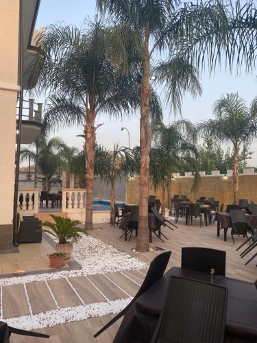 un patio avec des palmiers, des tables et des chaises dans l'établissement Corte Vena, à Bianco