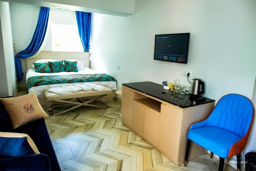 a room with a bed and a table and a blue chair at AVE MEDICA Apartments & SPA in Palanga