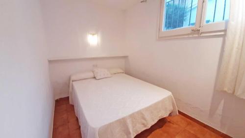 a small bedroom with a white bed in a room with a window at 1 Sire - Llafranc in Calella de Palafrugell