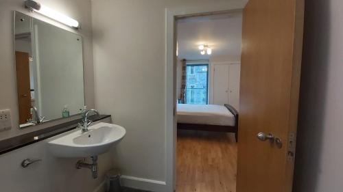 ein Bad mit einem Waschbecken, einem Spiegel und einem Bett in der Unterkunft Highland Club Scotland Apartments in Fort Augustus