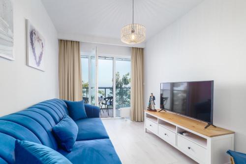 a living room with a blue couch and a tv at Ustronie Apartments z widokiem na morze 20 m do plaży in Ustronie Morskie