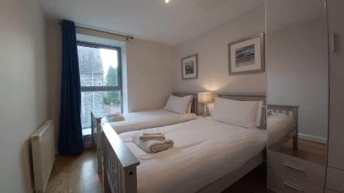 1 Schlafzimmer mit 2 Betten und einem Fenster in der Unterkunft Highland Club Scotland Apartments in Fort Augustus