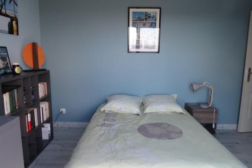 Cama en habitación con pared azul en Chambre chez Marie avec vue imprenable, en Sainte-Feyre