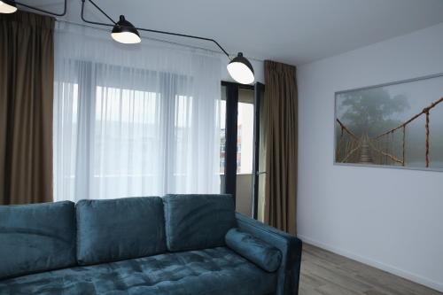 a living room with a blue couch in front of a window at ResHome Apartments&Rooms in Focşani