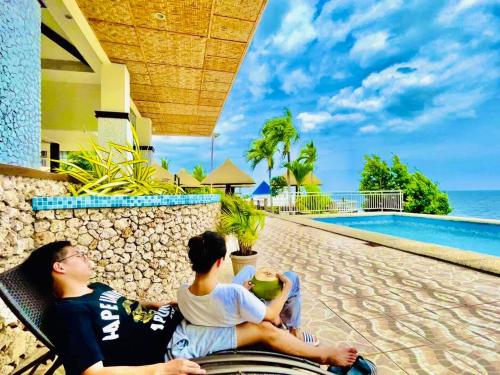 two men sitting on a bench next to a swimming pool at Azure Camotes Resort Hotel in Camotes Islands