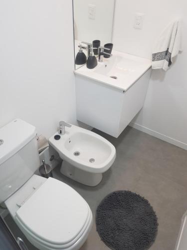 a white bathroom with a toilet and a sink at Ocean Drive Country - Punta del Este in Punta del Este