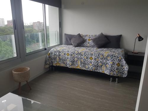 a bedroom with a bed with a floral bedspread and windows at Ocean Drive Country - Punta del Este in Punta del Este
