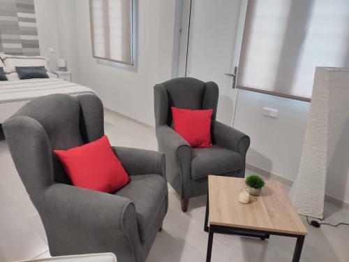 een slaapkamer met 2 stoelen en een bed met rode kussens bij Apartamento Madrid Norte in Madrid